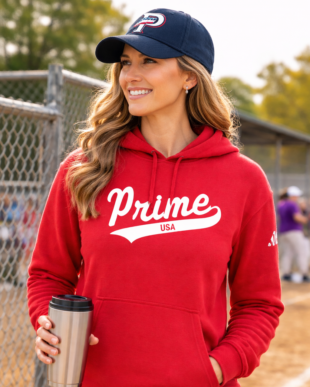 Woman wearing a red 'Prime USA' hoodie on a sports field