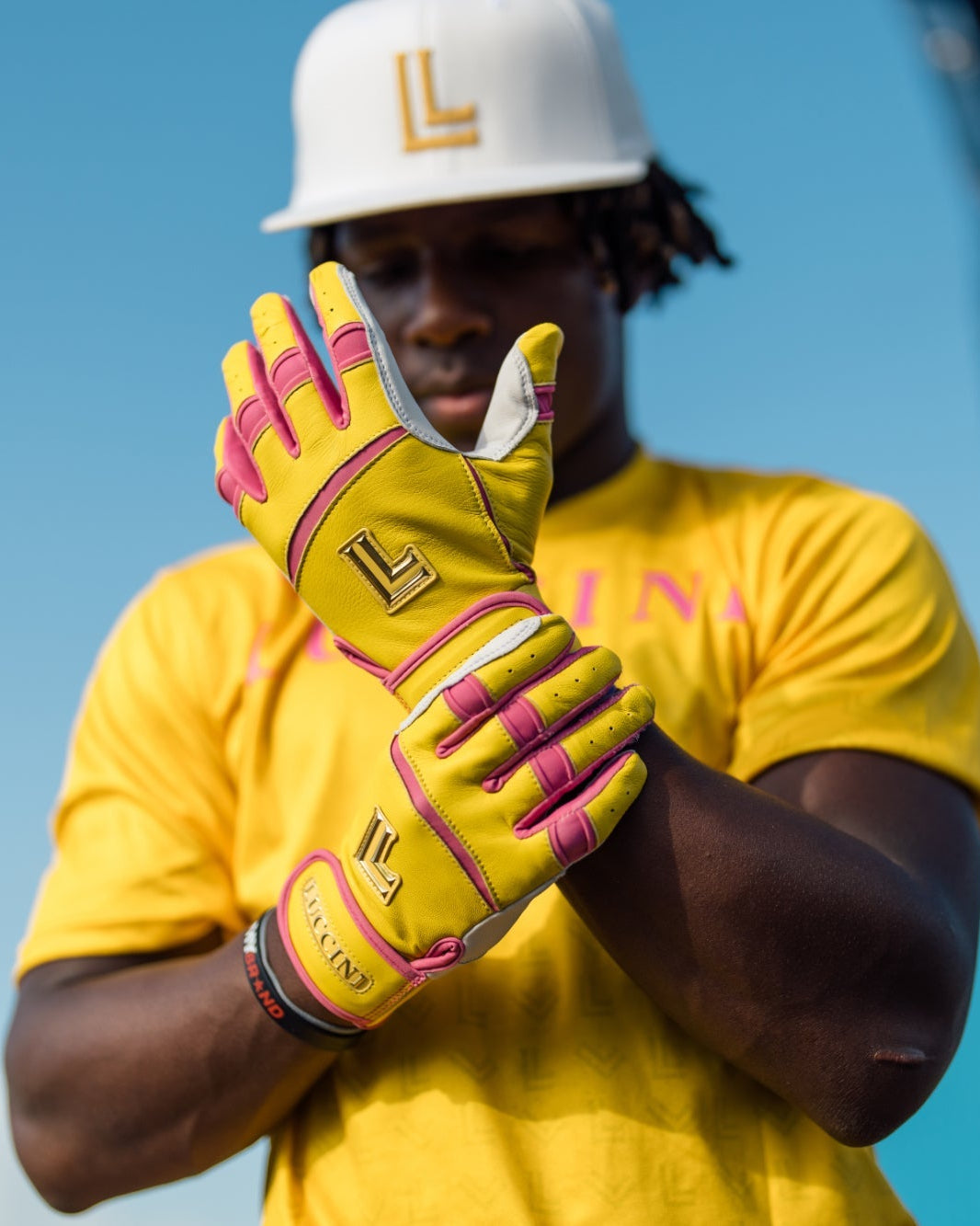 Jordan wearing yellow gloves with pink accents and a yellow shirt, standing against a blue sky.