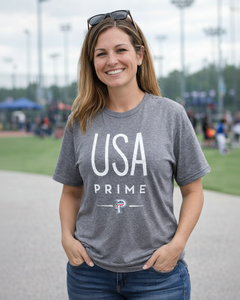 Woman wearing a gray 'USA Prime' t-shirt outdoors on a grassy area.